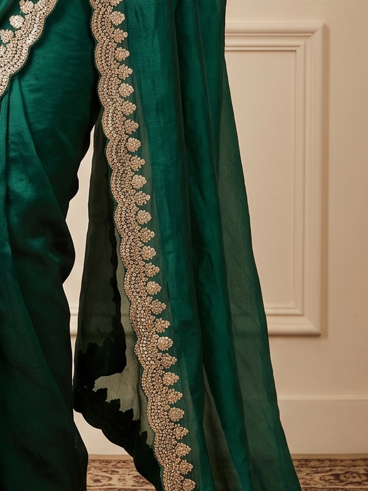 Pallu detail of green tissue saree showing ornamented surface design and zari border