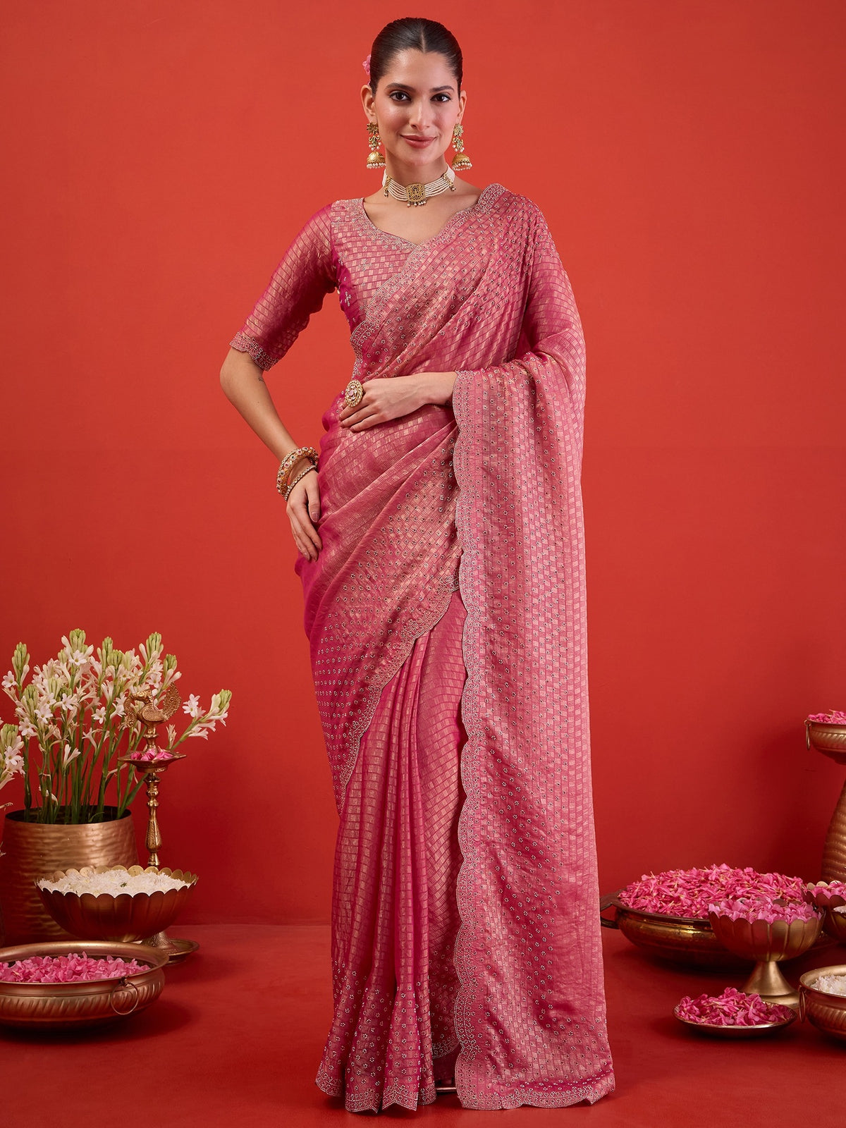 Woman wearing pink satin saree with ornamented surface design and pink blouse