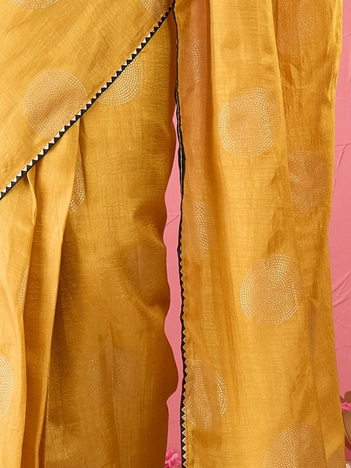 Pallu detail of mustard dola silk saree showing metallic foil print work and embellished border