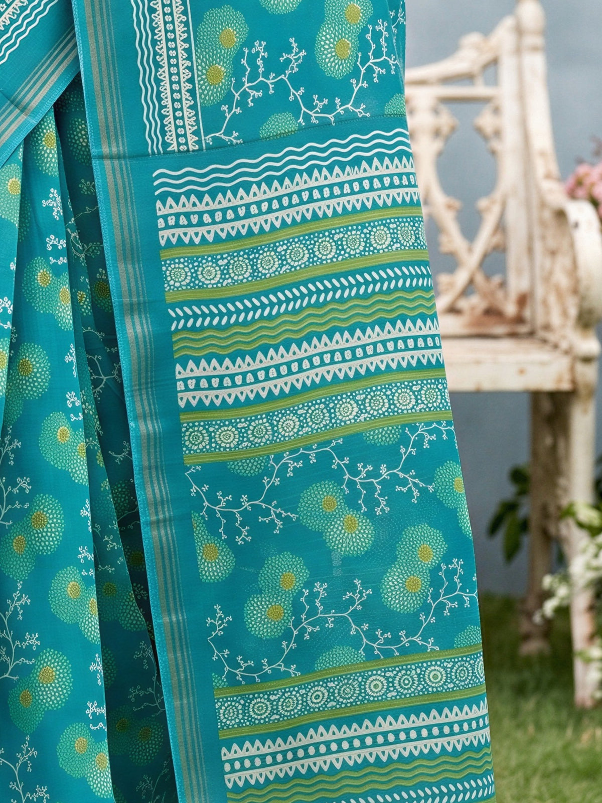Pallu detail of teal blue crepe saree showing botanical floral and leaf design and zari border