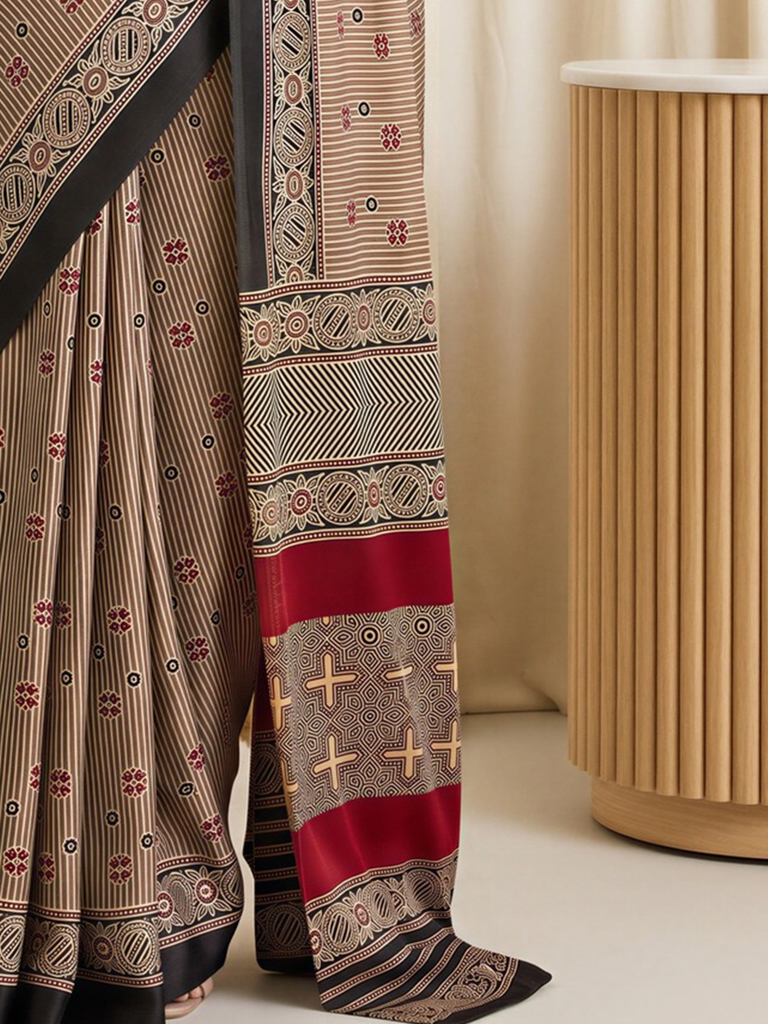 Pallu detail of beige satin saree showing striped pattern design and printed border