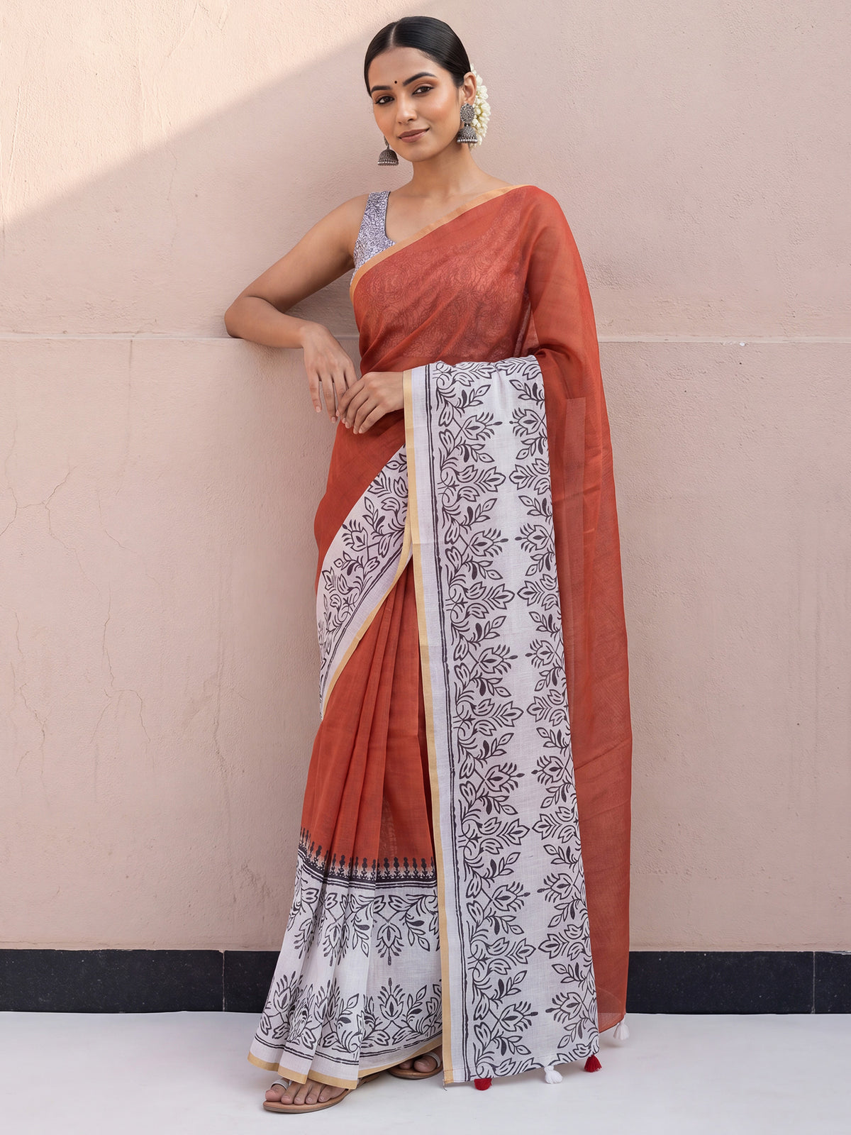 Woman wearing rust cotton linen saree with traditional indian print motifs and off white blouse