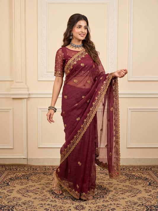 Woman wearing mauve tissue saree with ornamented surface design and mauve blouse