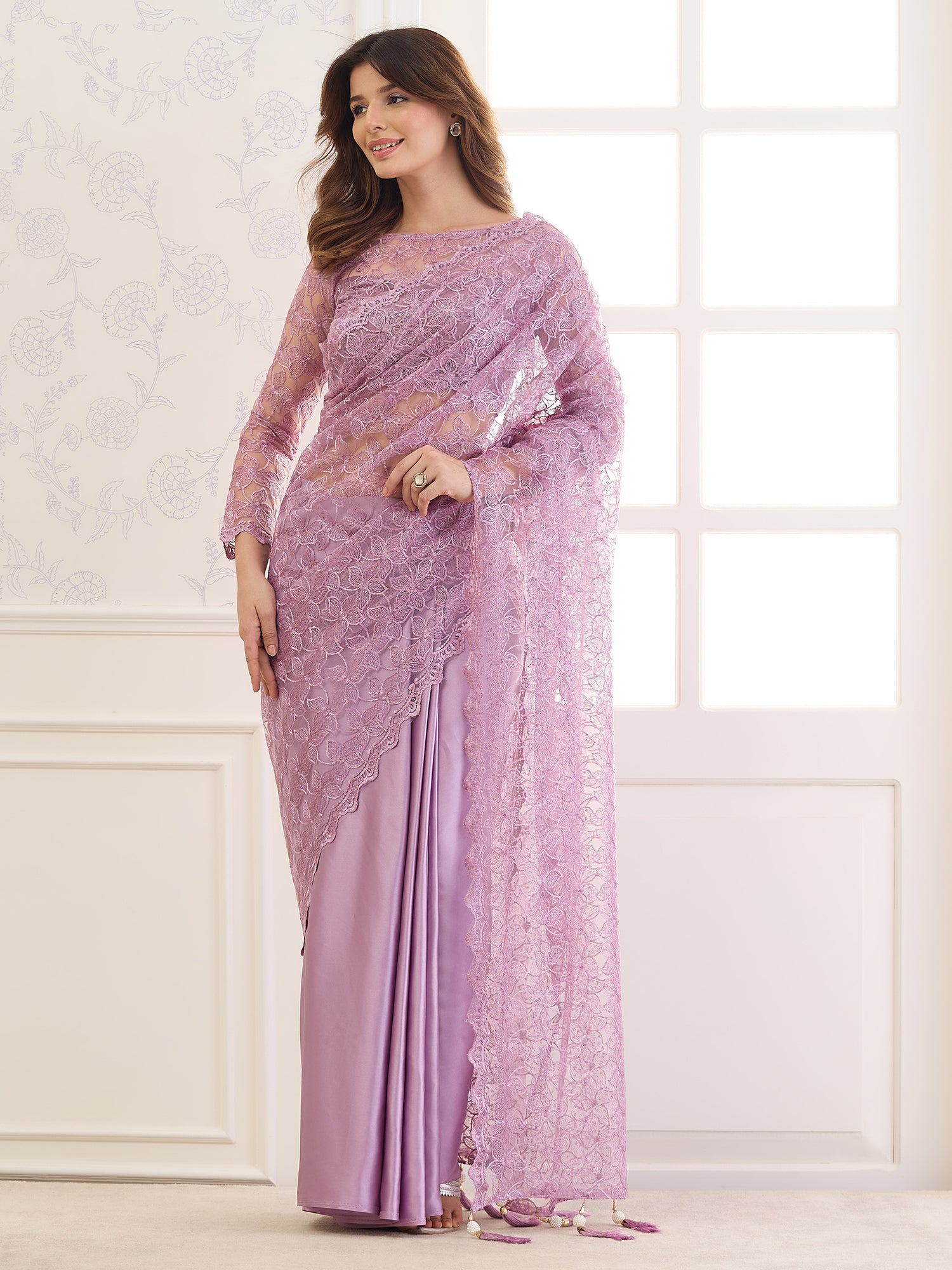 Woman wearing lavender net saree with ornamented surface design and lavender blouse