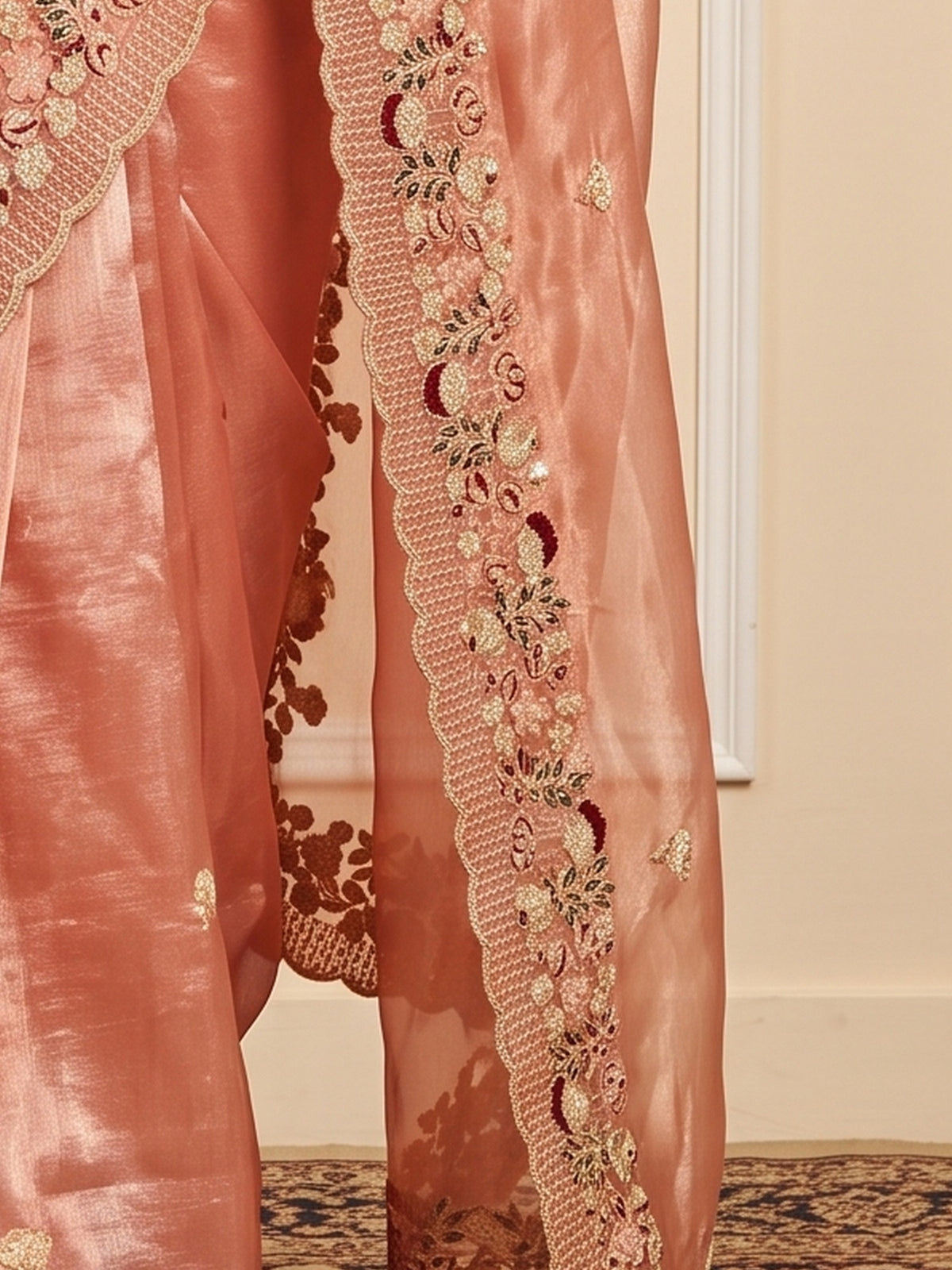 Pallu detail of peach organza saree showing embroidered motif work and embroidered border