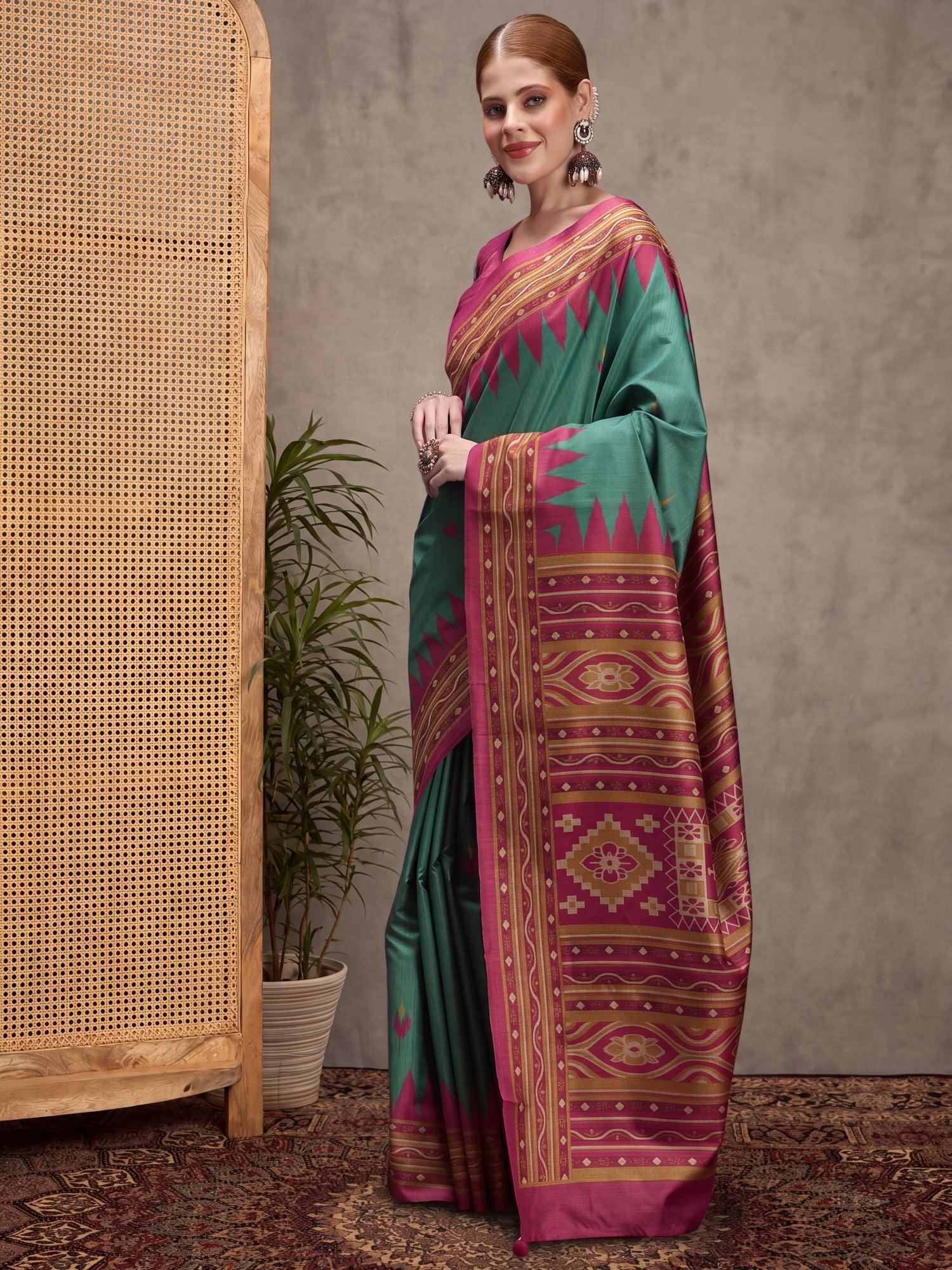 Woman wearing teal green silk blend saree with traditional indian motif work and magenta blouse