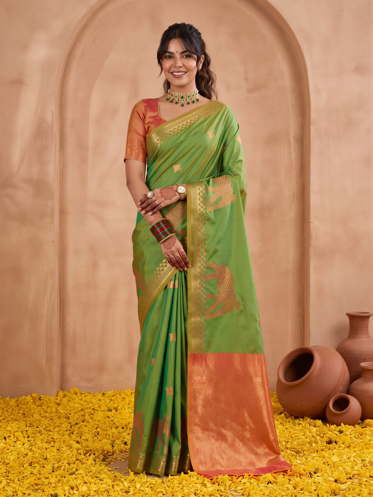 Woman wearing green silk saree with animal-print design and orange blouse