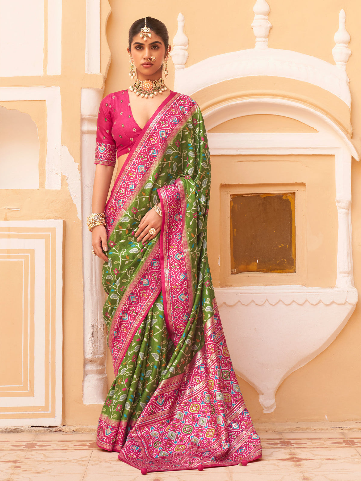 Woman wearing green silk blend saree with ikat resist-dyed pattern and pink blouse