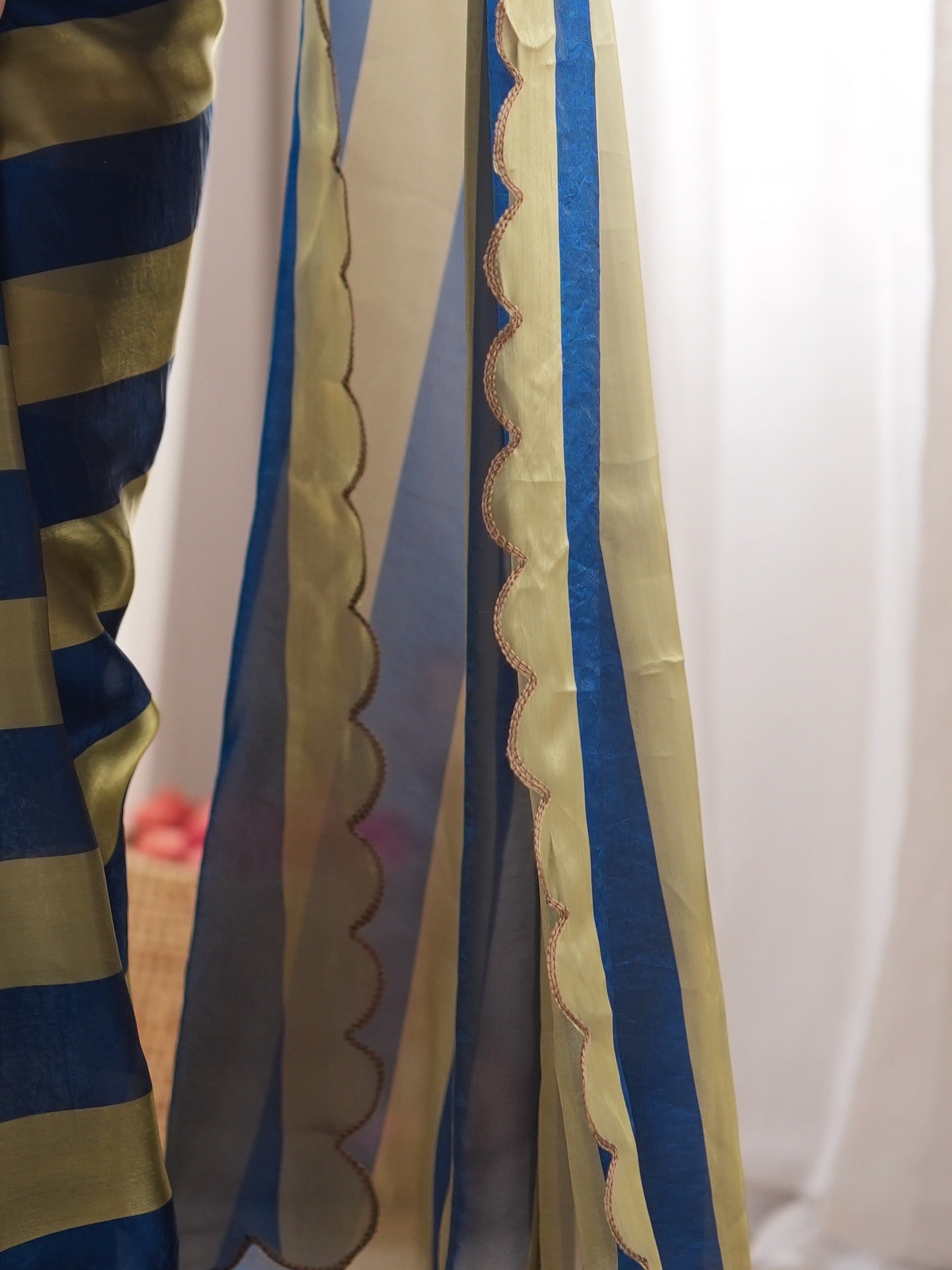 Pallu detail of teal blue satin saree showing striped pattern design and embroidered border