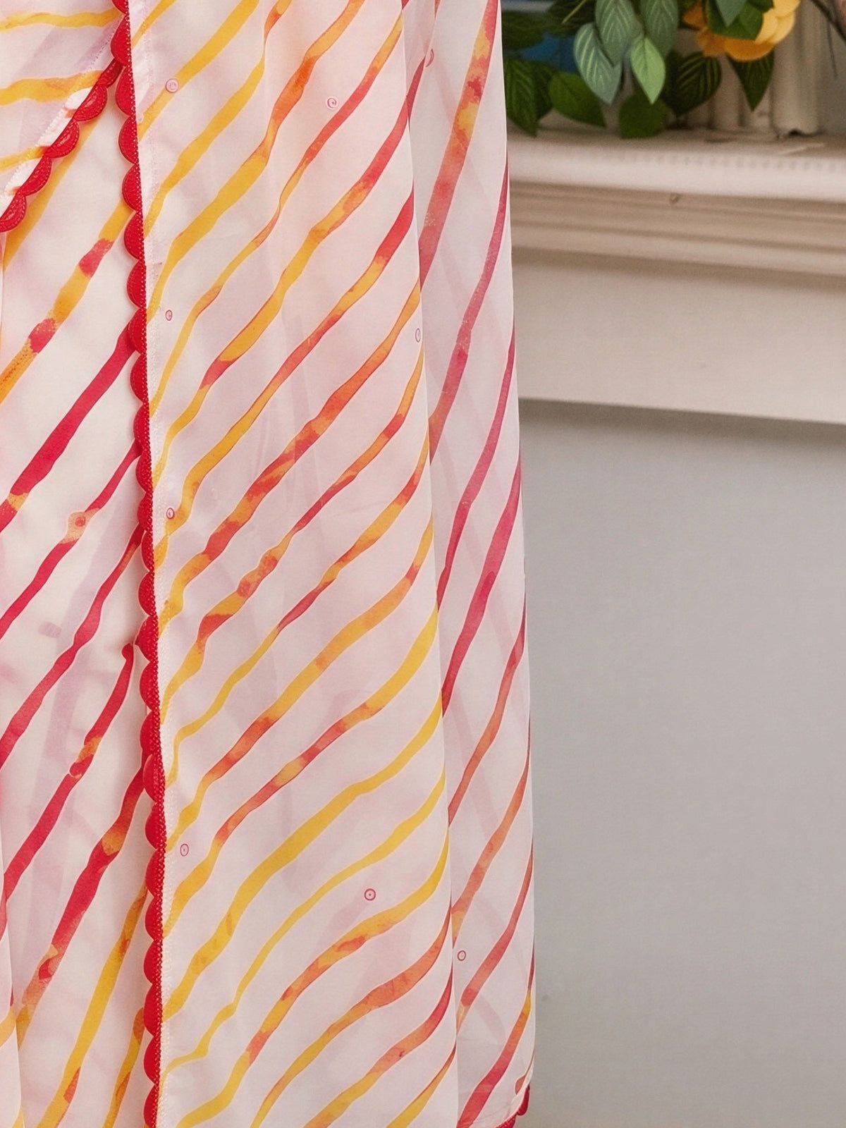 Pallu detail of off white georgette saree showing leheriya design and embroidered border