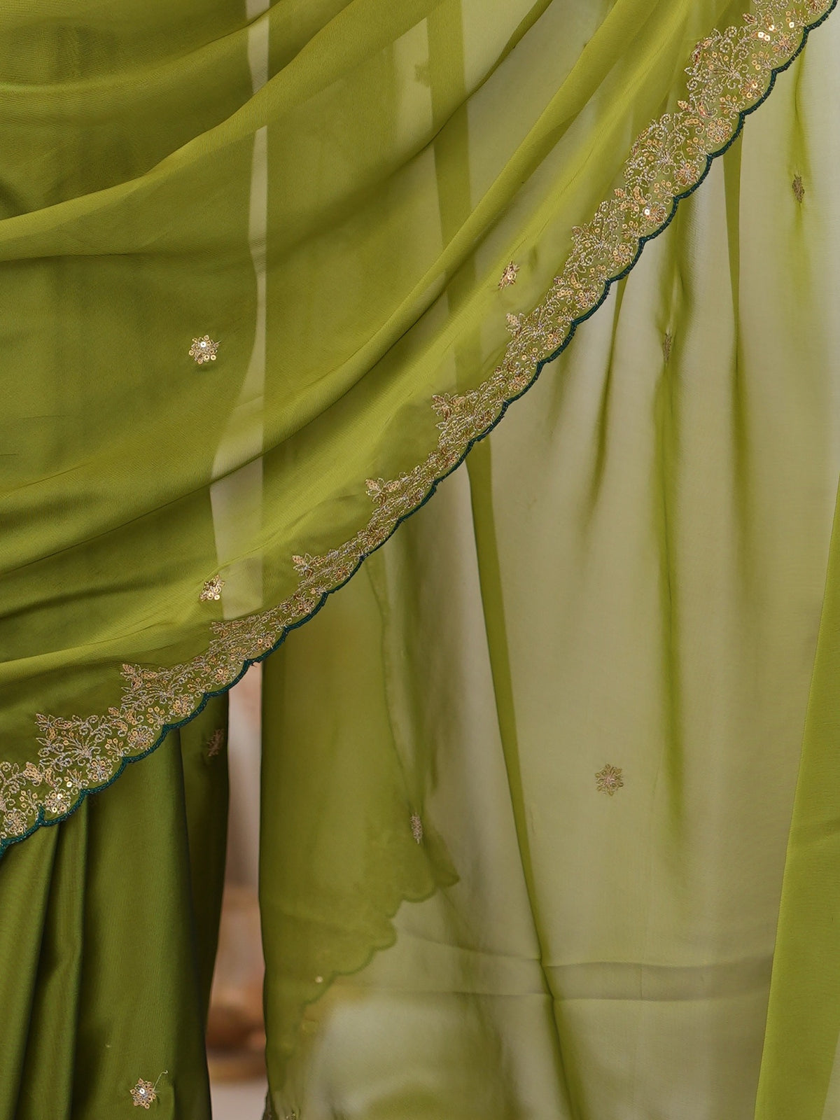 Pallu detail of olive georgette saree showing ornamented surface design and scallop border