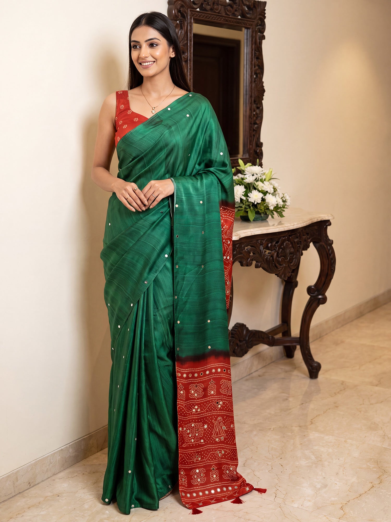 Woman wearing green silk blend saree with bandhani tie-dye dot work and red blouse