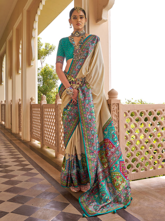 Woman wearing beige silk blend saree with traditional indian motif work and teal blue blouse