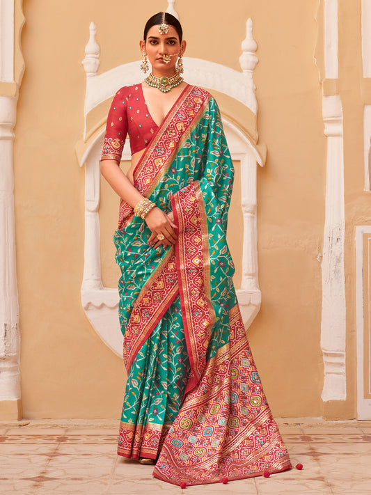 Woman wearing teal green silk blend saree with ikat resist-dyed pattern and red blouse