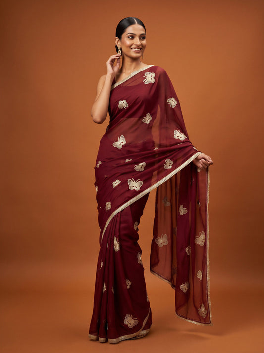 Woman wearing maroon georgette saree with embroidered motif work and maroon blouse