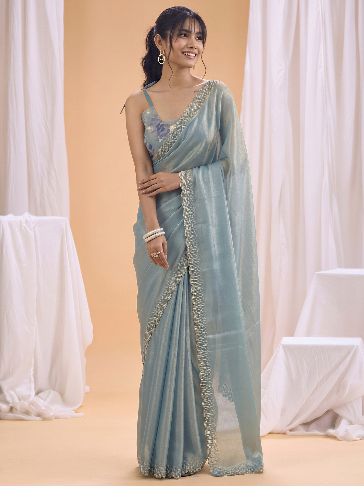 Woman wearing light blue silk saree with ornamented surface design and light blue blouse