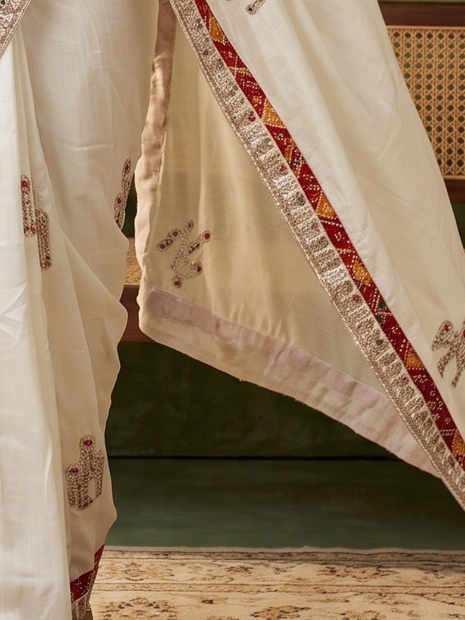 Pallu detail of white dola silk saree showing ornamented surface design and zari border