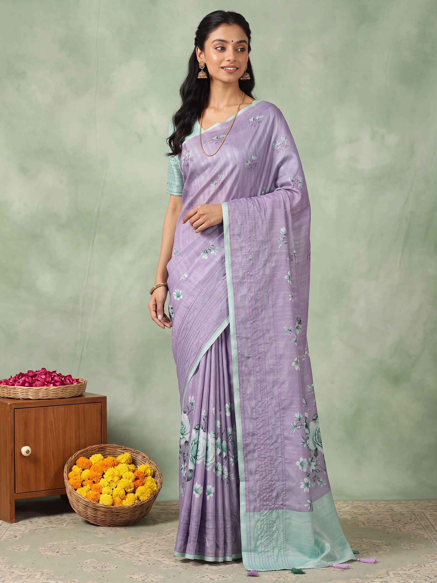 Woman wearing lavender silk blend saree with all-over floral design and turquoise blouse