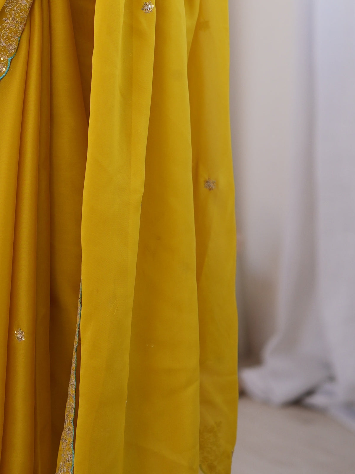 Pallu detail of yellow georgette saree showing ornamented surface design and scallop border