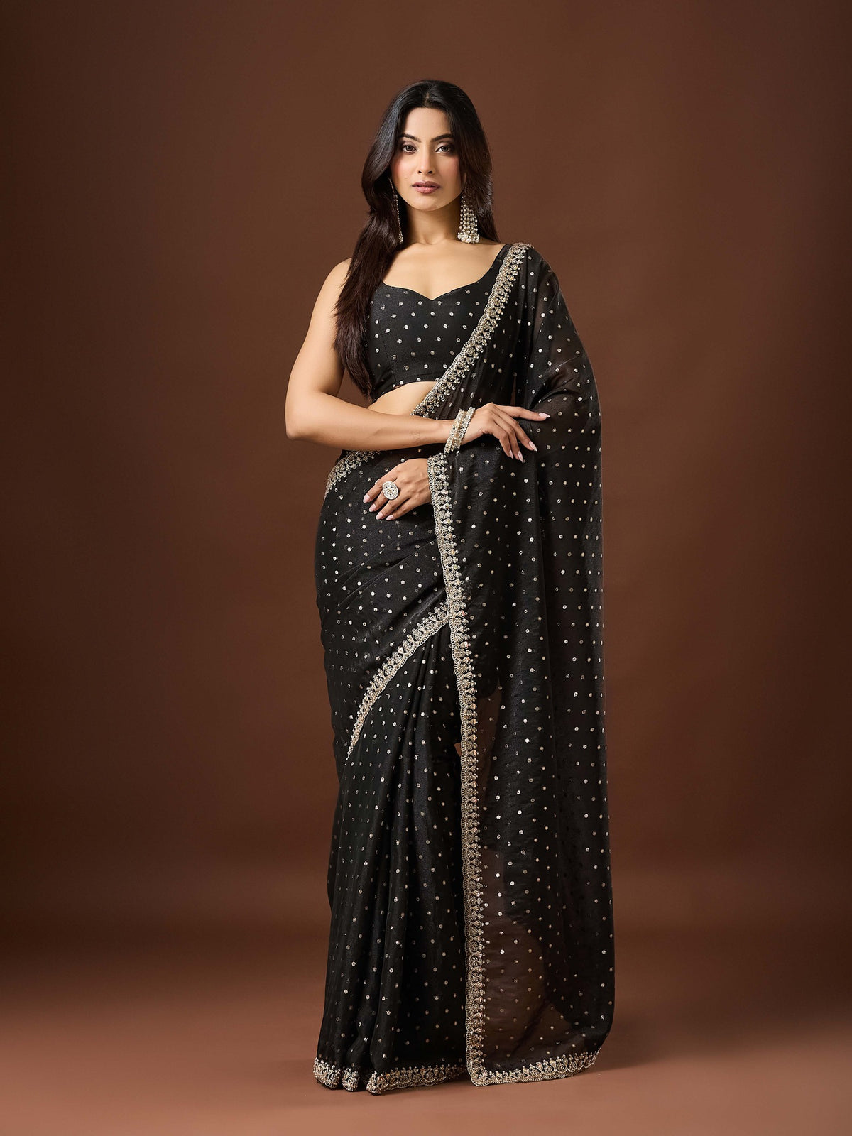 Woman wearing black georgette saree with ornamented surface design and black blouse