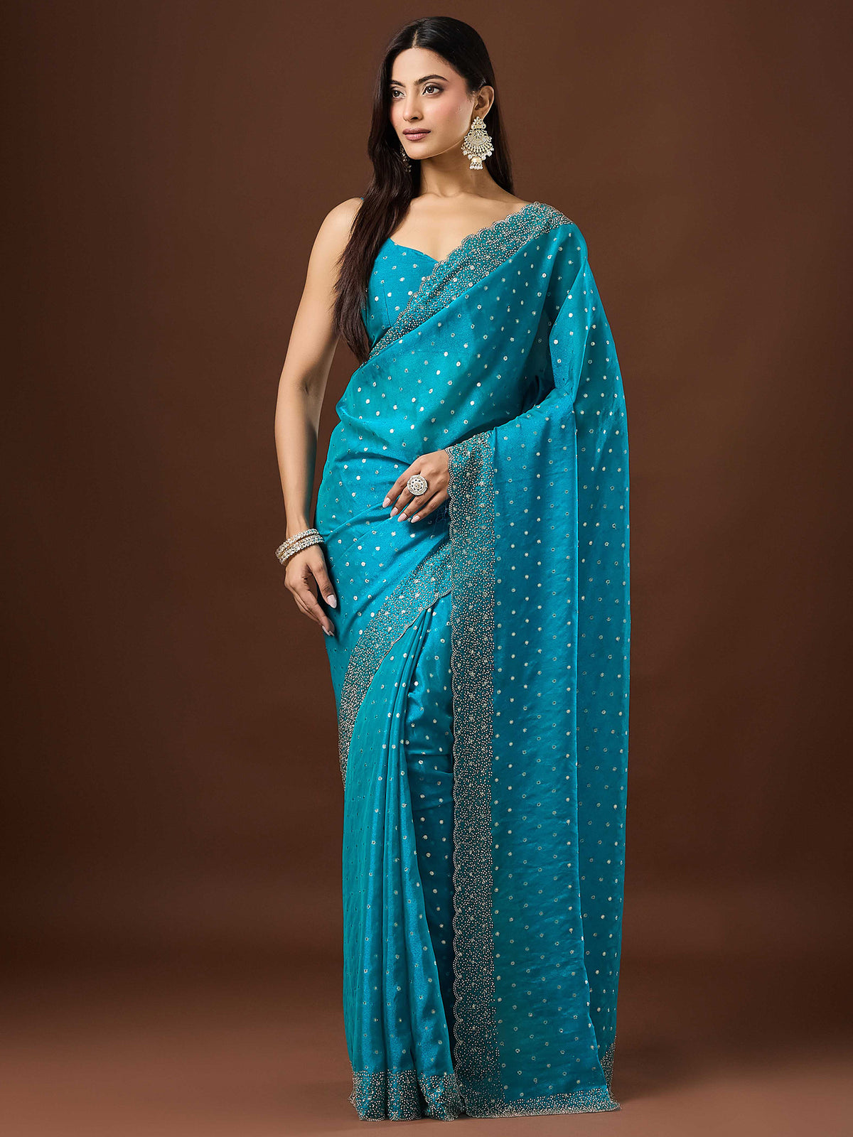 Woman wearing turquoise silk blend saree with ornamented surface design and turquoise blouse