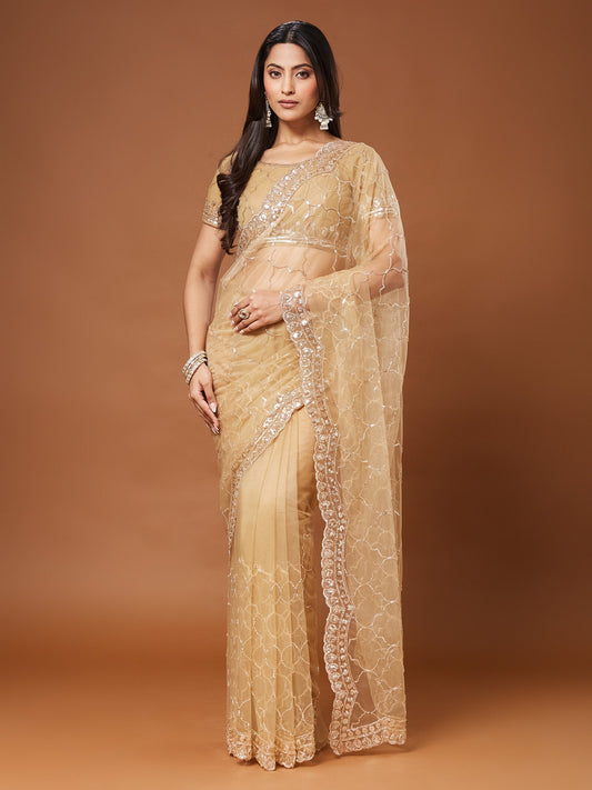 Woman wearing beige net saree with ornamented surface design and beige blouse