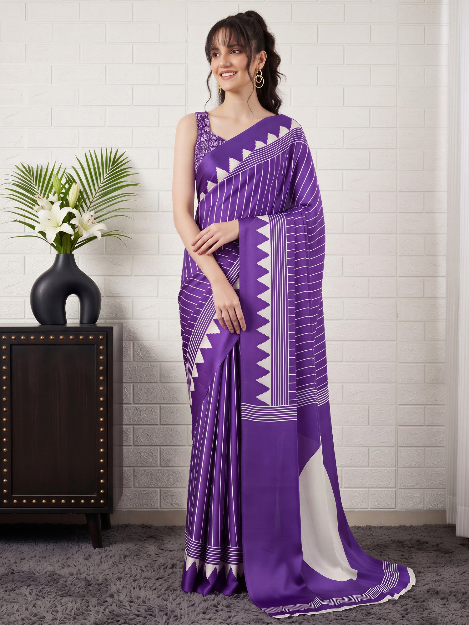 Woman wearing purple satin saree with striped pattern design and purple blouse