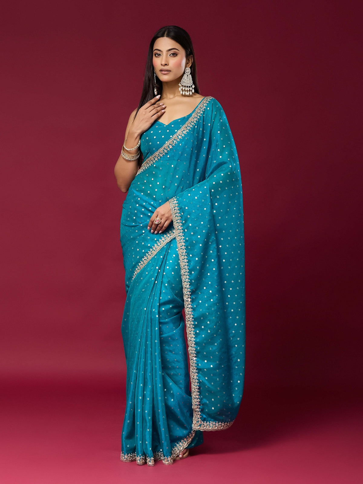 Woman wearing turquoise blue georgette saree with ornamented surface design and turquoise blue blouse