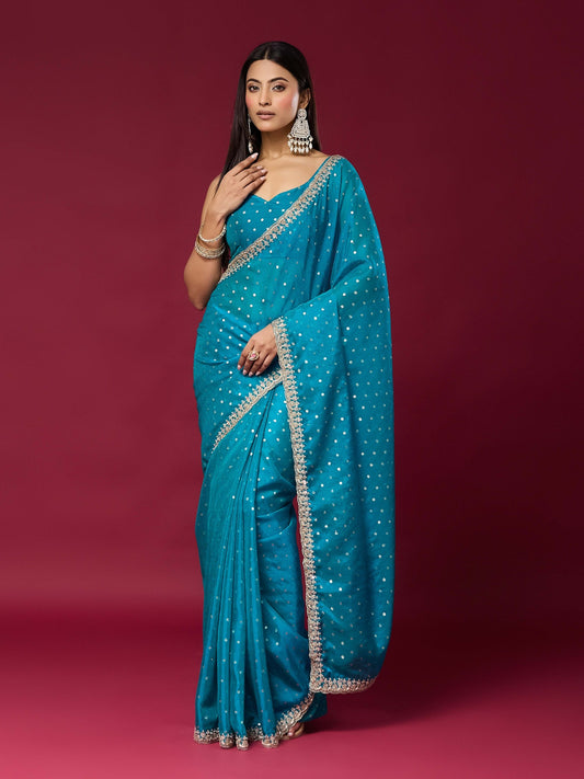 Woman wearing turquoise blue georgette saree with ornamented surface design and turquoise blue blouse