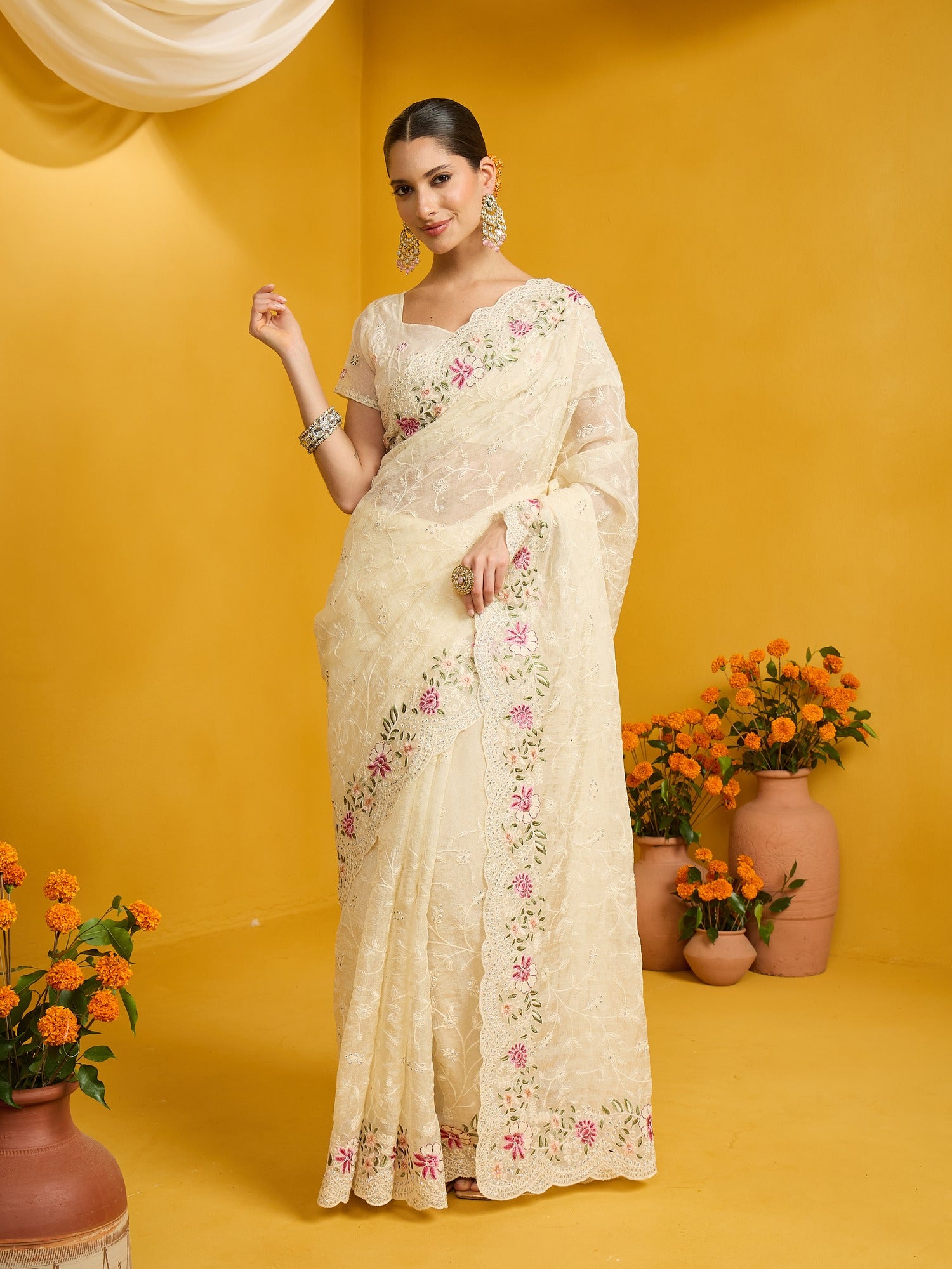 Woman wearing cream organza saree with ornamented surface design and cream blouse