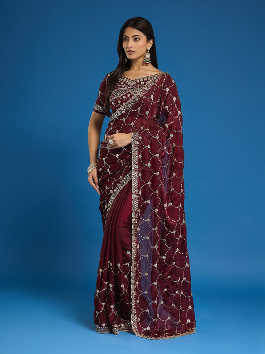Woman wearing maroon satin saree with ornamented surface design and maroon blouse