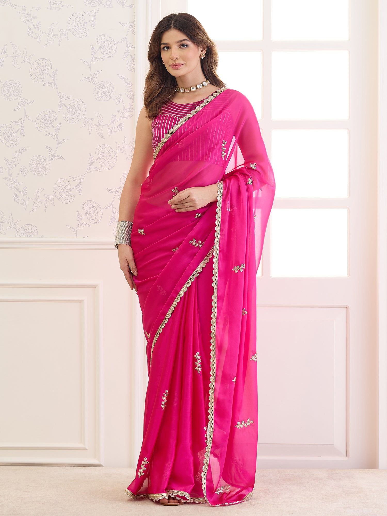 Woman wearing pink pure georgette saree with ornamented surface design and pink blouse