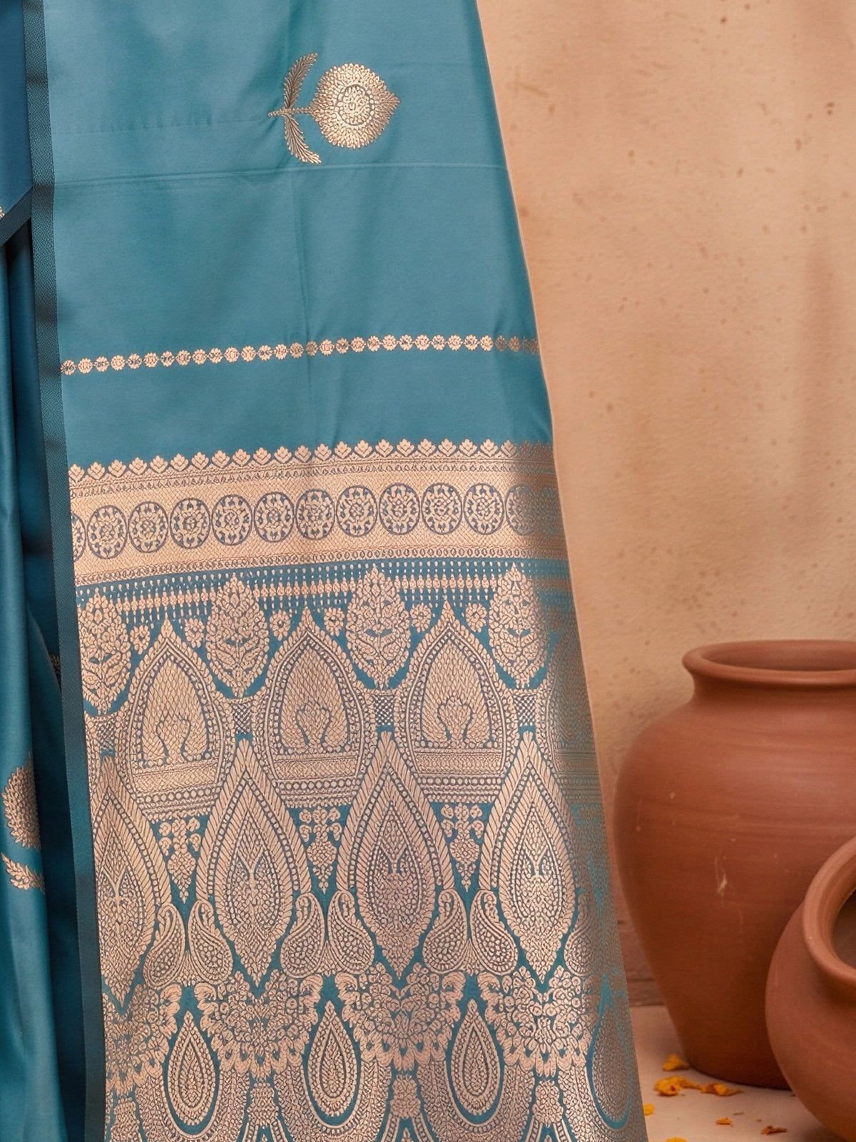 Pallu detail of teal blue satin silk saree showing traditional indian motif work and no border border