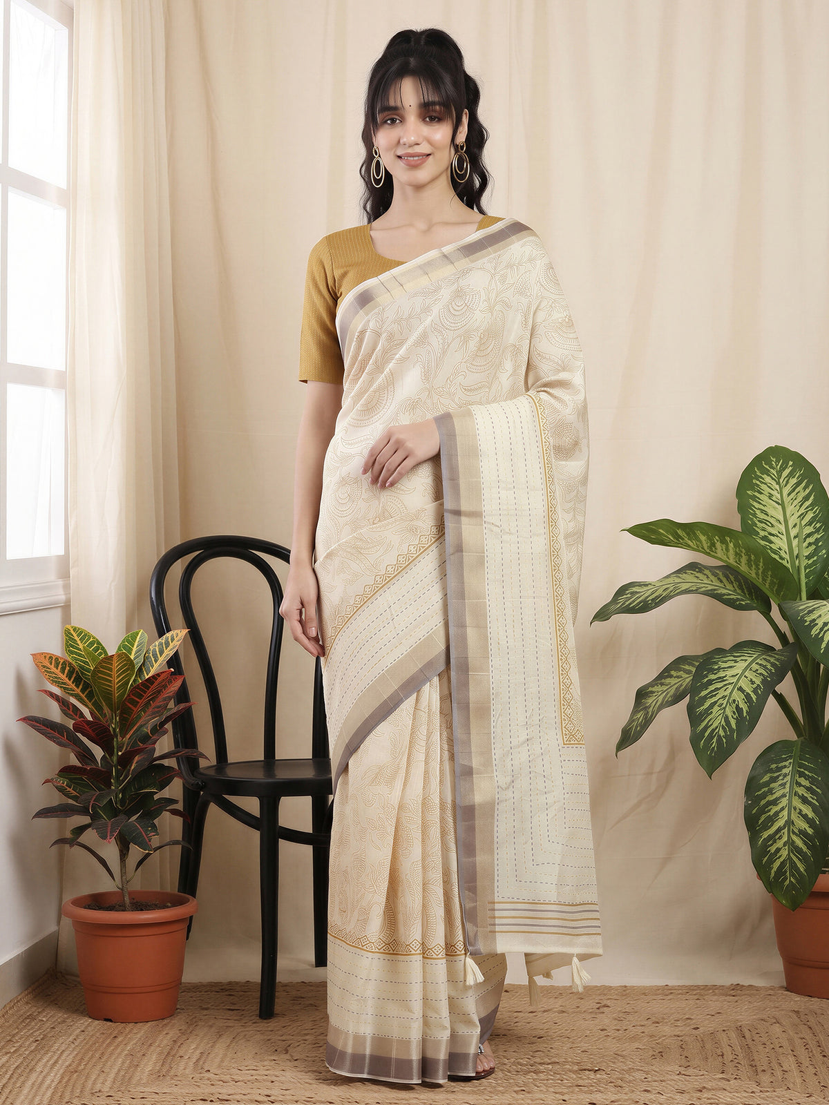 Woman wearing off white cotton silk saree with ornamented surface design and mustard blouse
