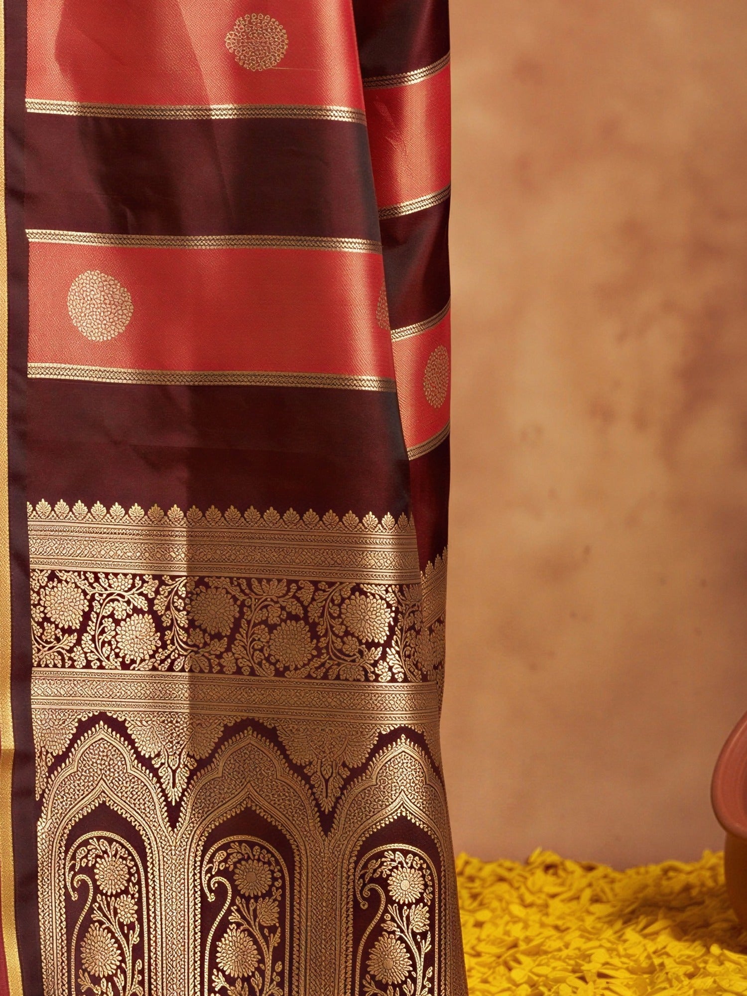 Pallu detail of maroon satin saree showing traditional indian motif work and zari border