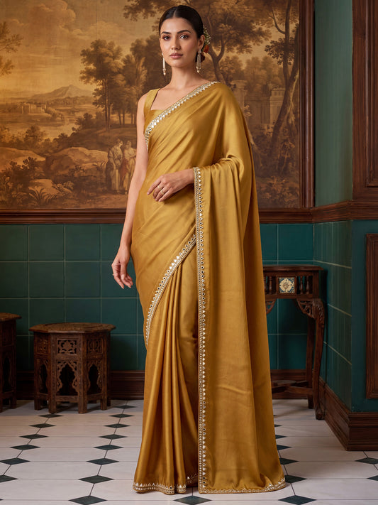 Woman wearing mustard satin saree with clean solid-tone finish and mustard blouse