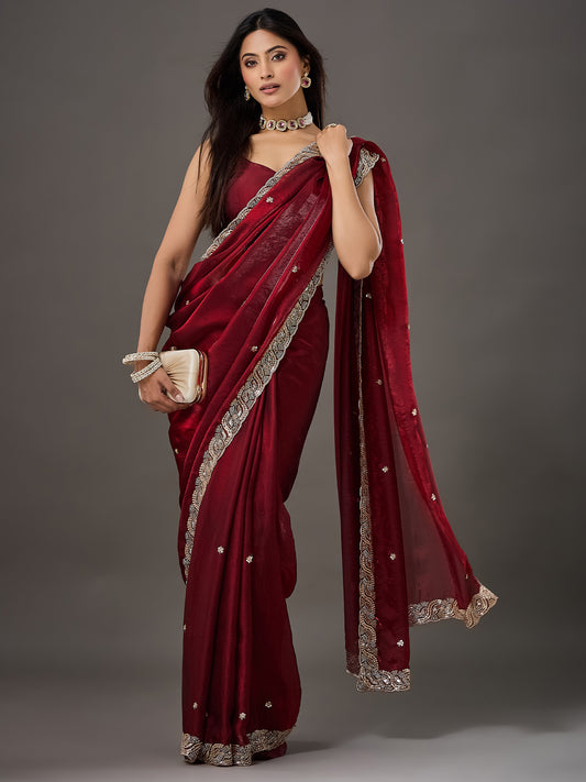 Woman wearing maroon satin saree with ornamented surface design and maroon blouse