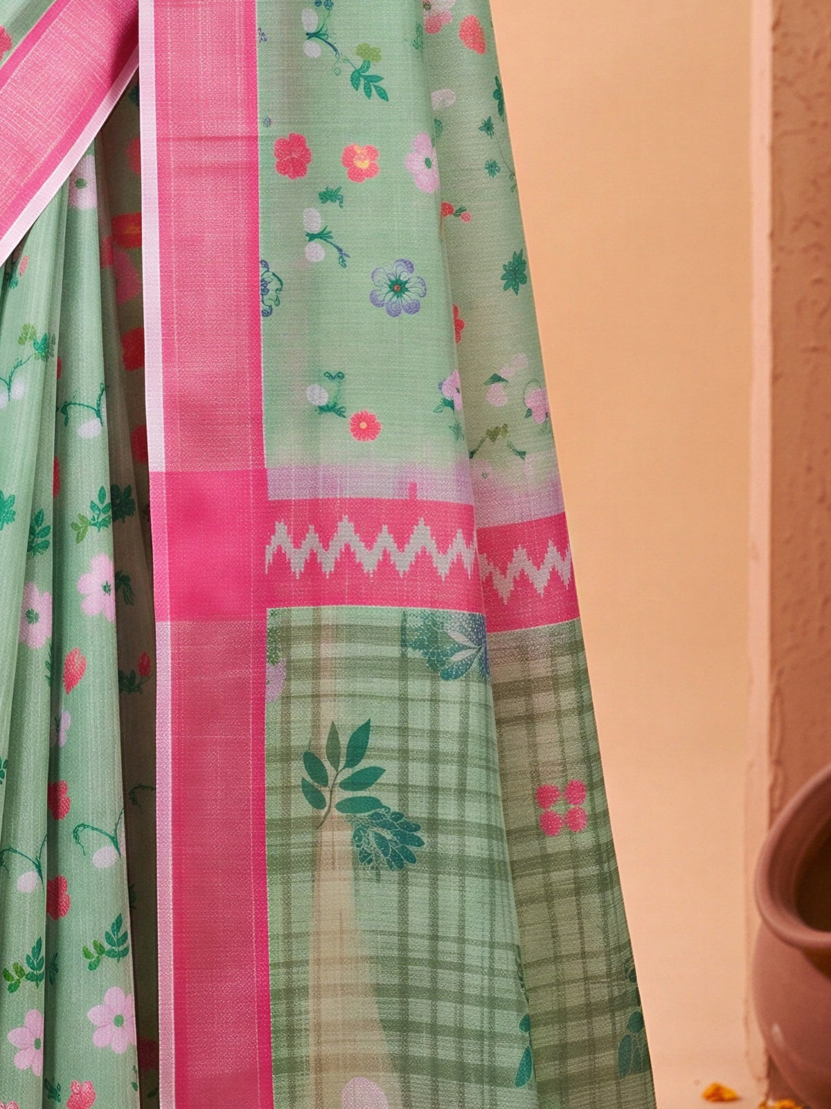 Pallu detail of sea green cotton linen saree showing all-over floral design and zari border