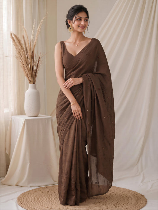 Woman wearing brown poly crepe saree with traditional indian motif work and brown blouse