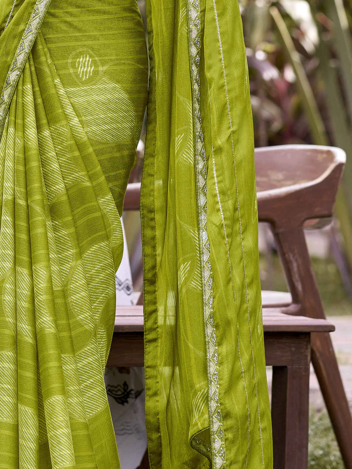 Pallu detail of lime green chiffon saree showing traditional indian motif work and embellished border