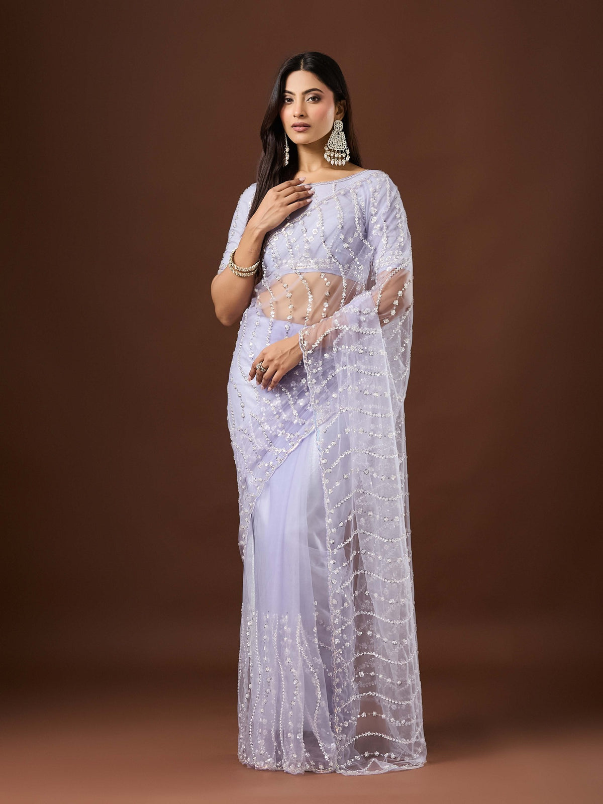 Woman wearing lavender net saree with ornamented surface design and lavender blouse