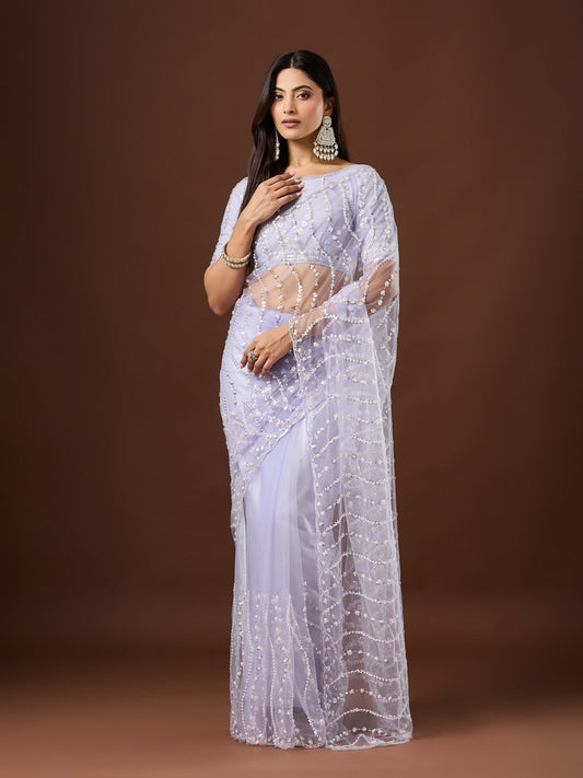 Woman wearing lavender net saree with ornamented surface design and lavender blouse
