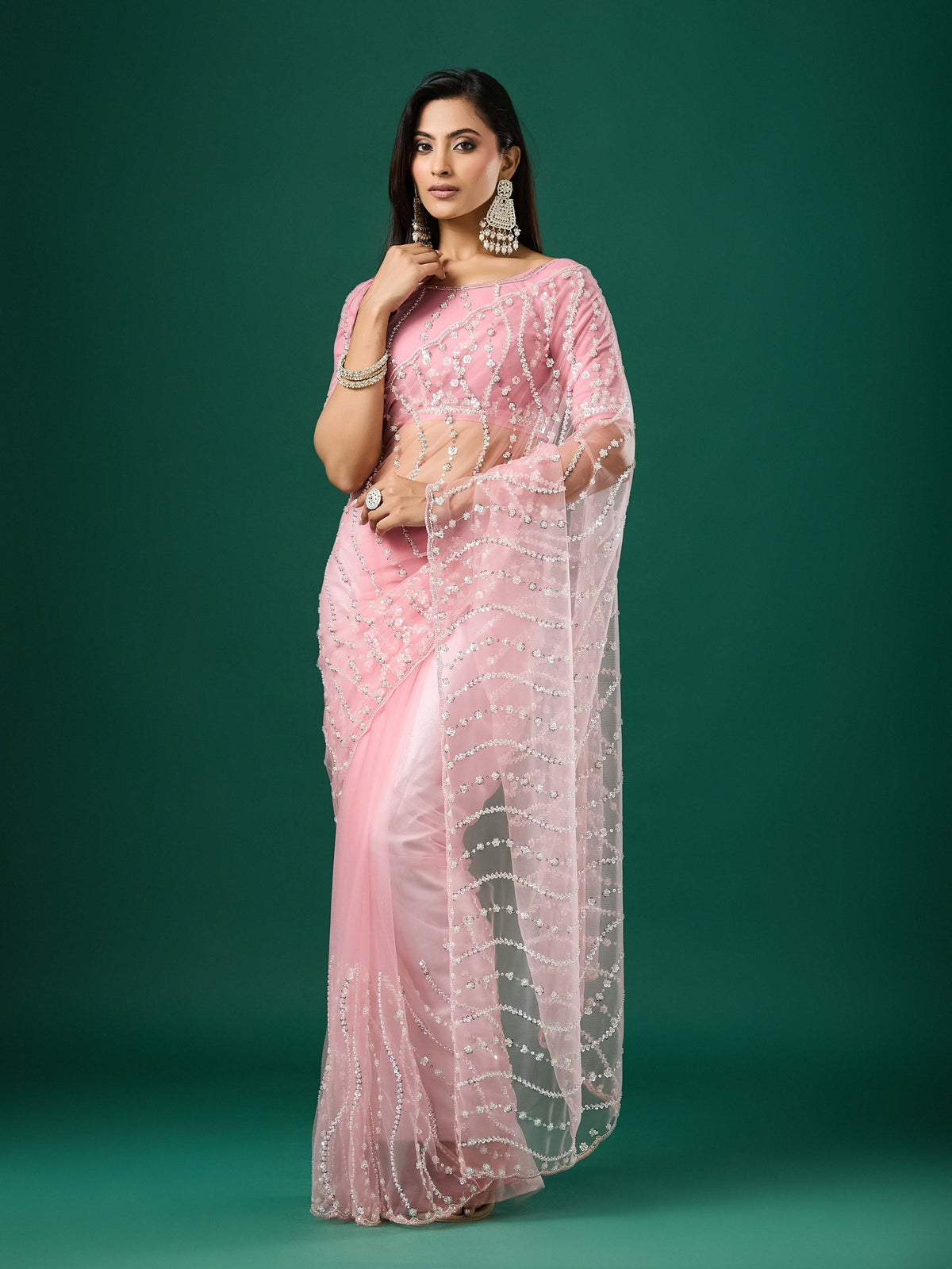 Woman wearing pink net saree with ornamented surface design and pink blouse