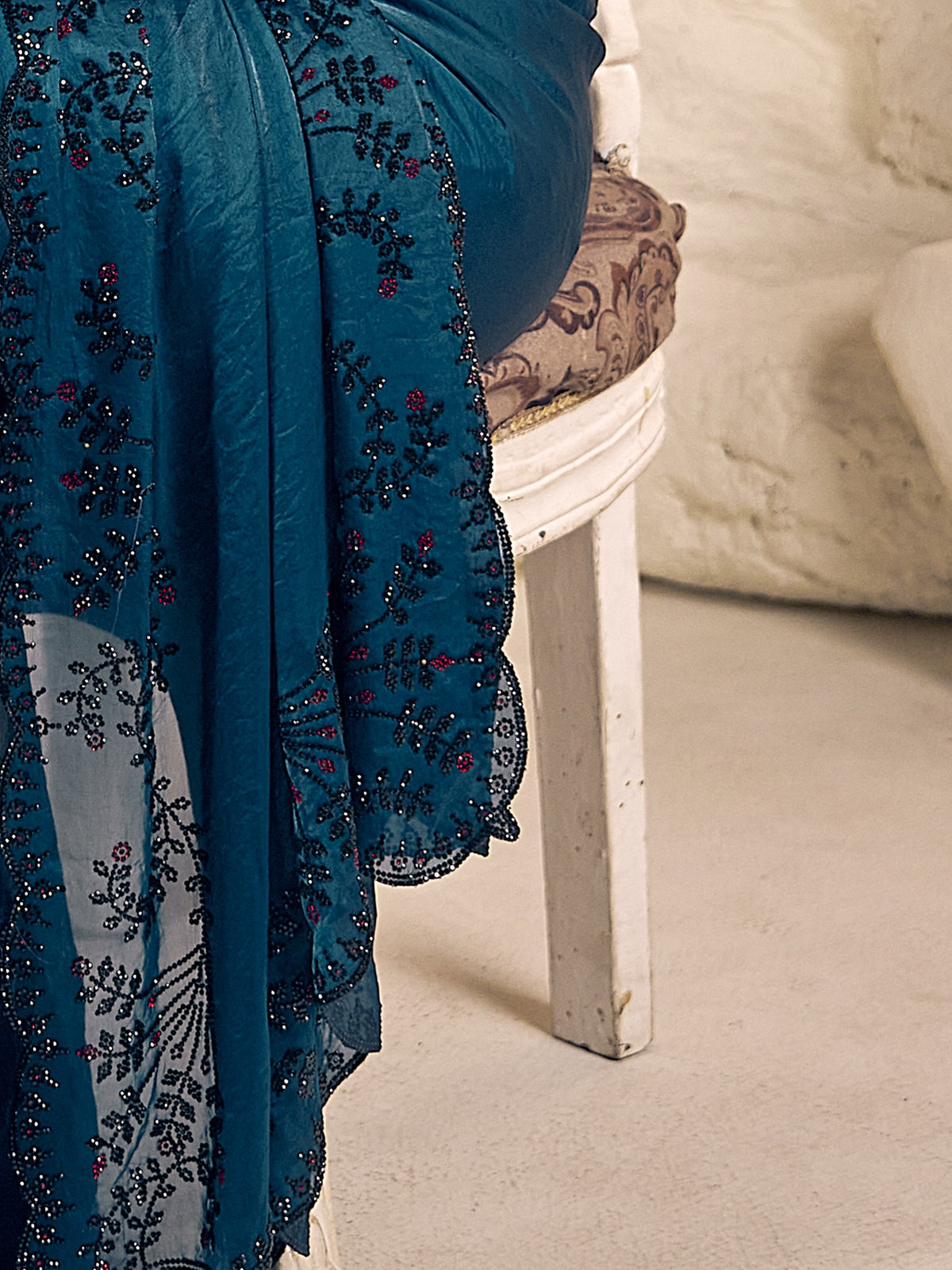 Pallu detail of teal blue satin silk saree showing ornamented surface design and embellished border