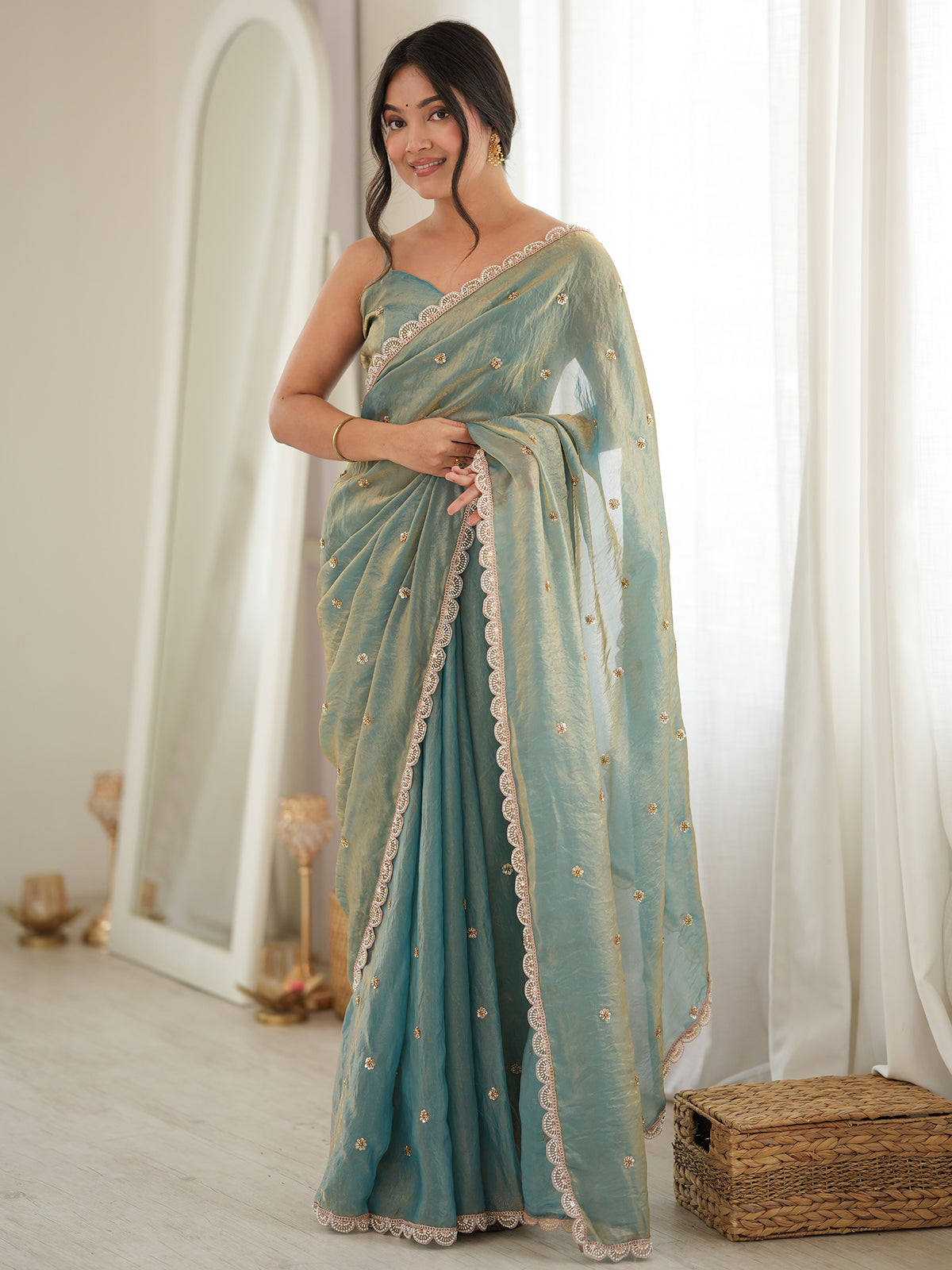 Woman wearing light blue satin saree with ornamented surface design and light blue blouse