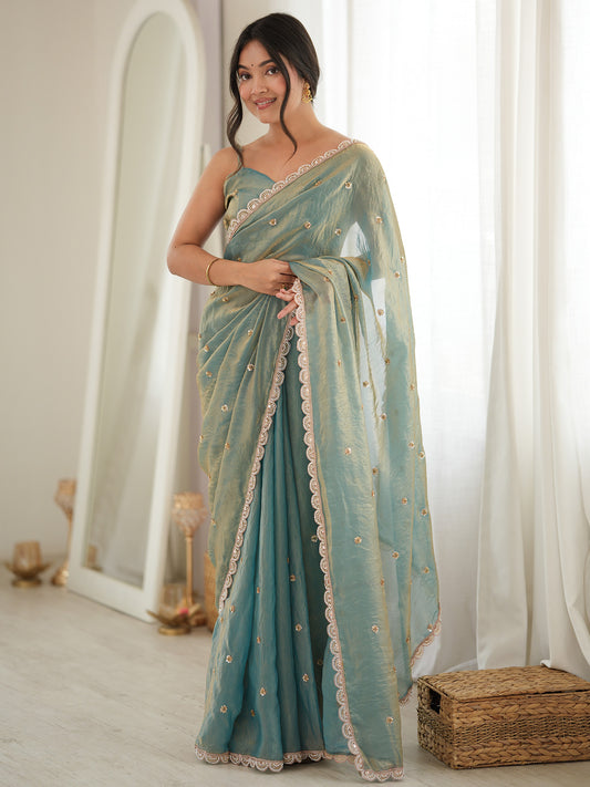 Woman wearing light blue satin saree with ornamented surface design and light blue blouse