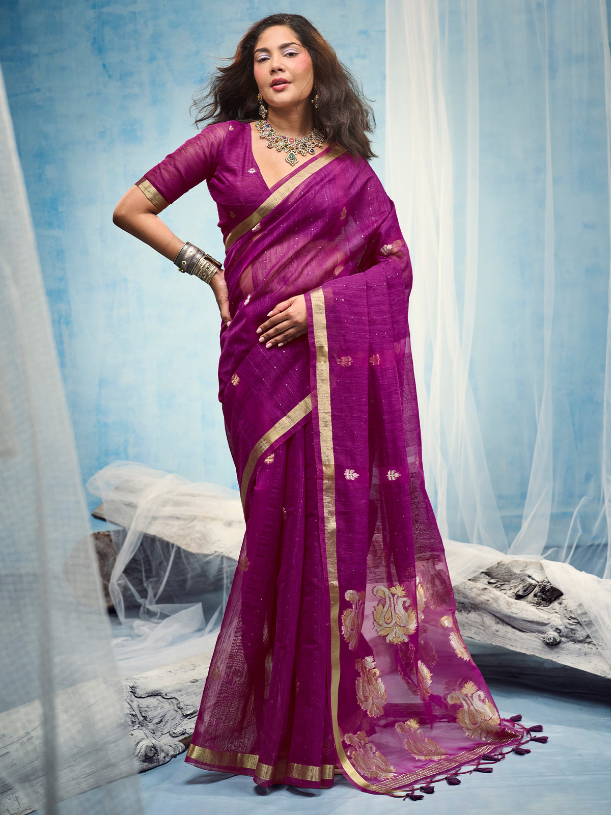 Woman wearing magenta muga silk saree with zari butta (metallic motif) work and magenta blouse