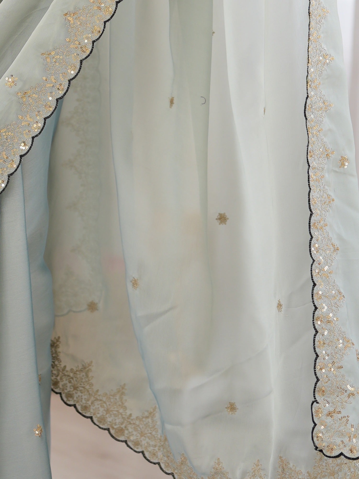 Pallu detail of light blue georgette saree showing ornamented surface design and scallop border