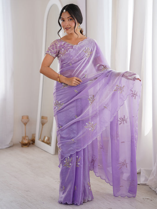 Woman wearing lavender satin saree with ornamented surface design and lavender blouse