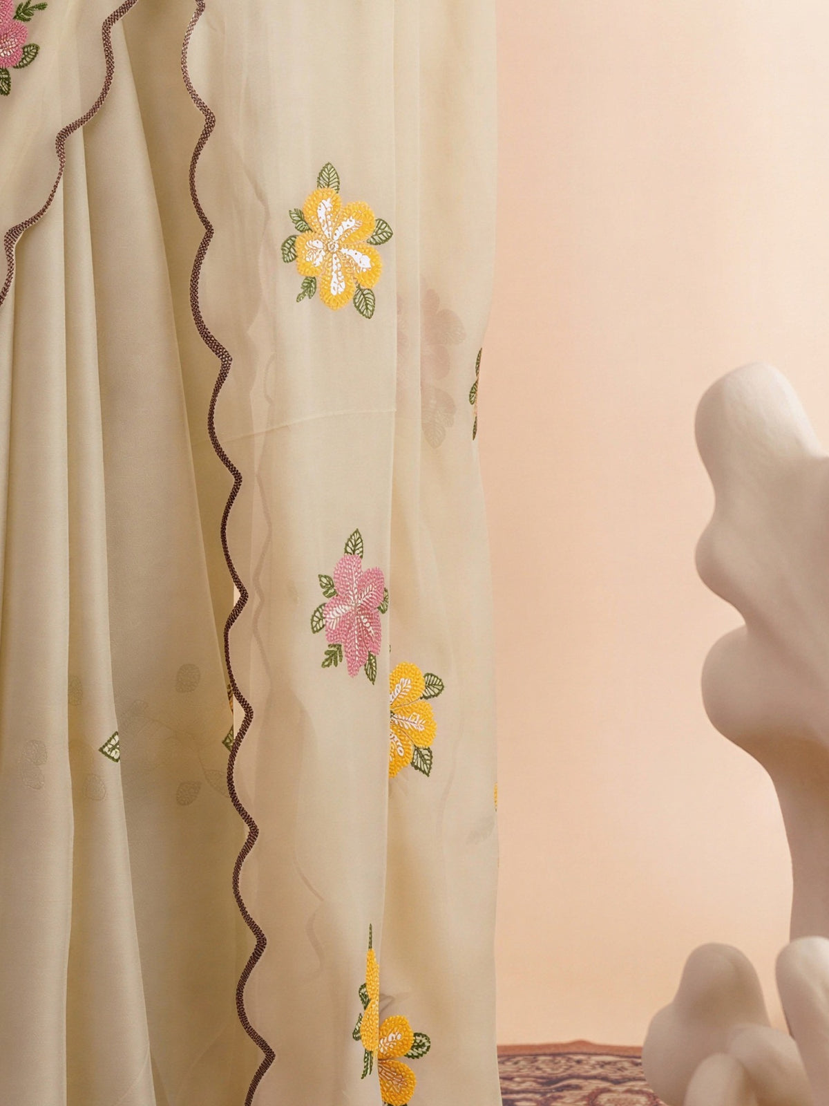 Pallu detail of cream georgette saree showing embroidered motif work and embroidered border